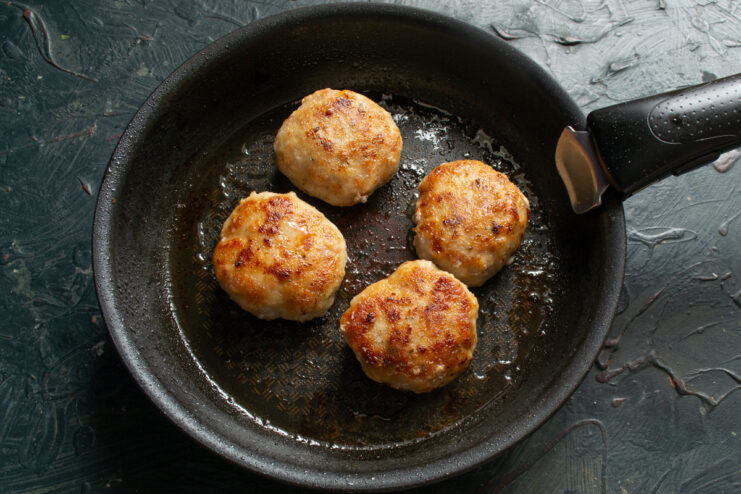 Frying the patties in oil Frying breaded meat patties in a skillet until golden brown