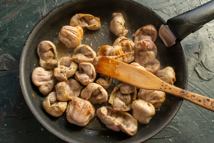 Searing chicken gizzards with spices in a hot skillet