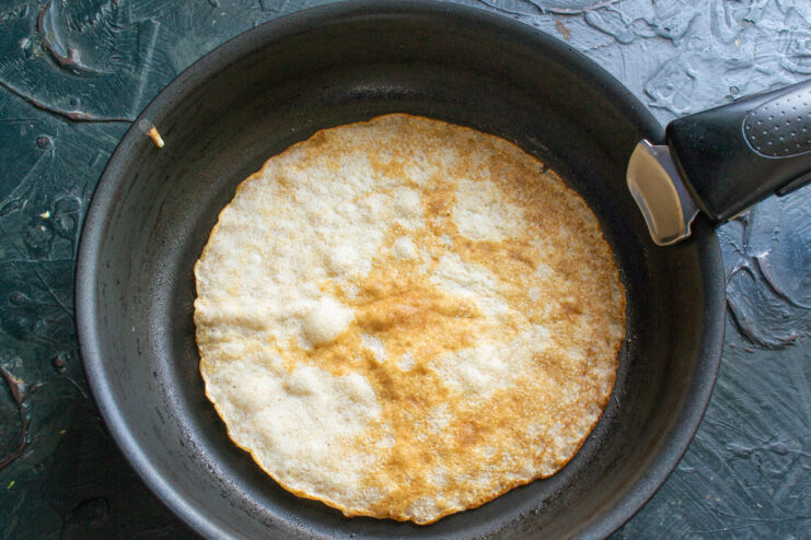 Frying the crepes Frying a golden brown crepe in a hot skillet