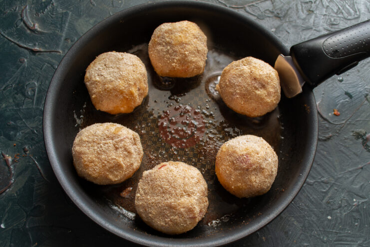 Frying breaded fish meatballs in a skillet