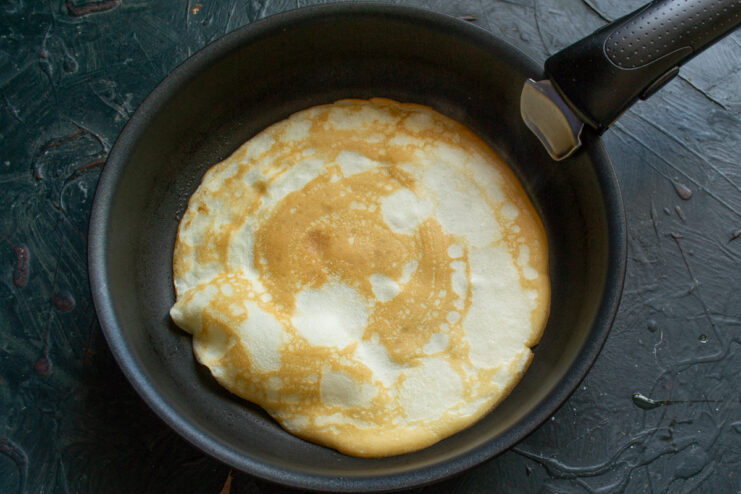 Cooking a thin round crepe in a hot skillet