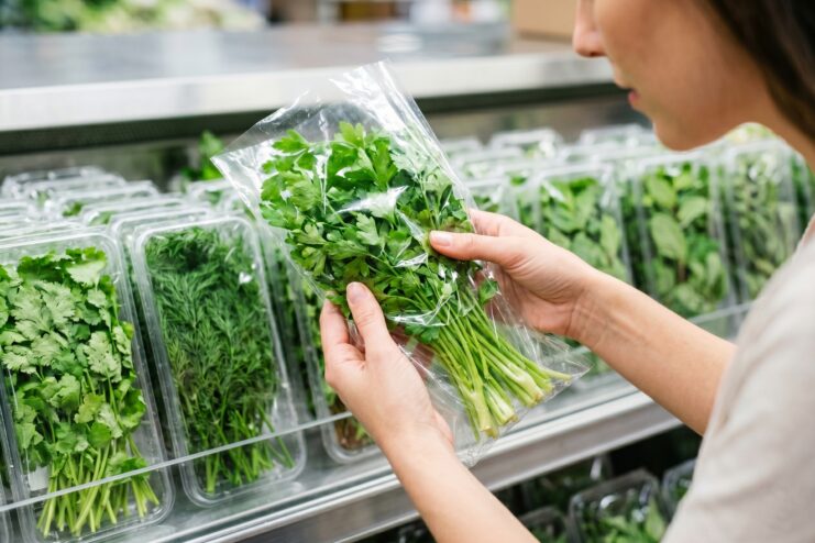 Selecting Fresh Herbs at the Supermarket Woman carefully inspecting a bunch of fresh parsley in a grocery store