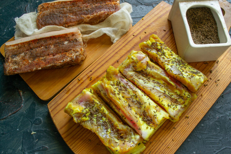 Coating the Pork Belly with Caraway Seeds Golden wet-cured pork belly generously sprinkled with toasted caraway seeds