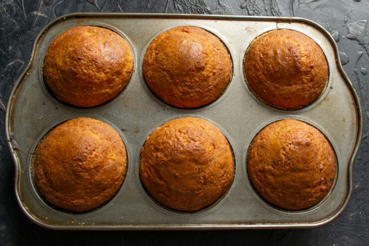 Baking muffins to a golden brown Golden brown baked muffins in a metal muffin tin checked for doneness