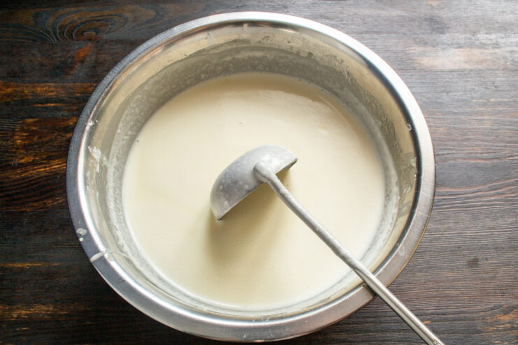 Thin crepe batter in a mixing bowl with a ladle.