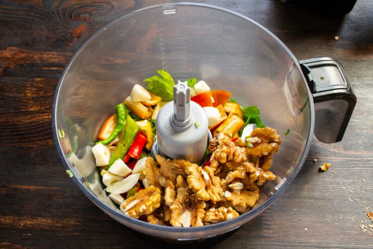 Adding walnuts for a thick texture Whole walnut halves added to the vegetable mixture inside the blender.