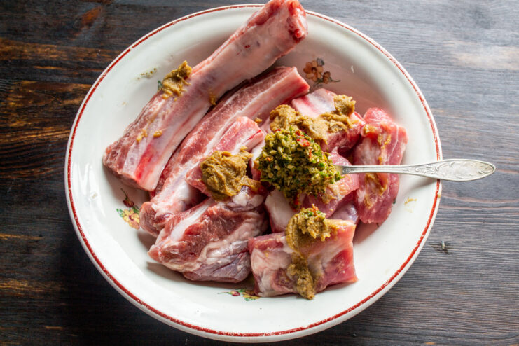 Adding the Spices Adding mustard, adjika paste, and honey to pork ribs in a bowl