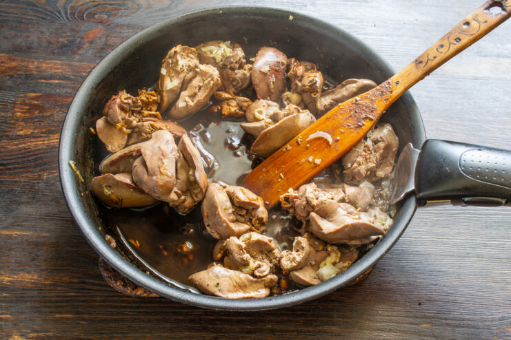 Pouring red wine into the skillet Adding dry red wine to sautéed chicken livers in a pan