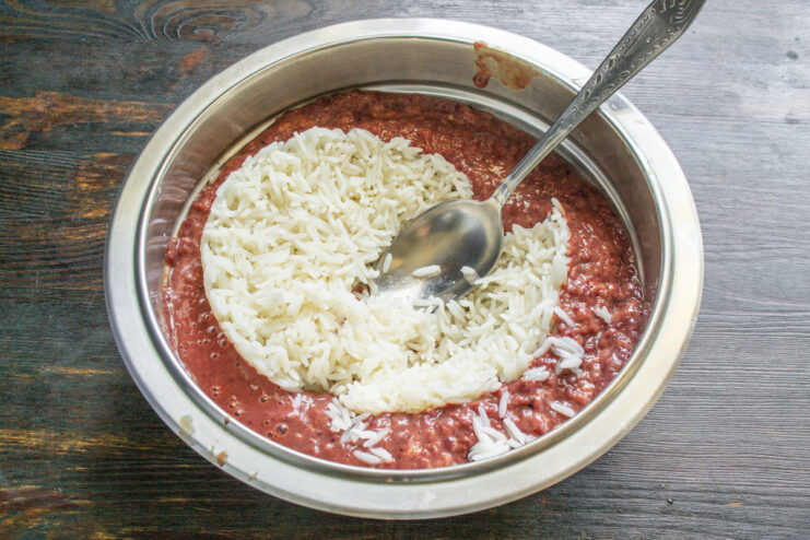 Combining Rice And Liver Adding cooked white rice to a bowl of ground chicken liver.