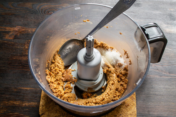 Adding sugar and a pinch of salt to the blended peanut mixture.