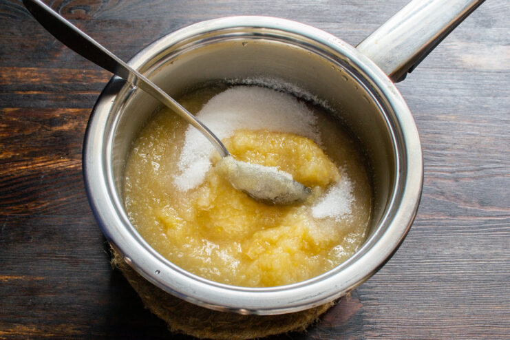 Adding sugar Pouring granulated sugar into smooth apple purée in a saucepan.