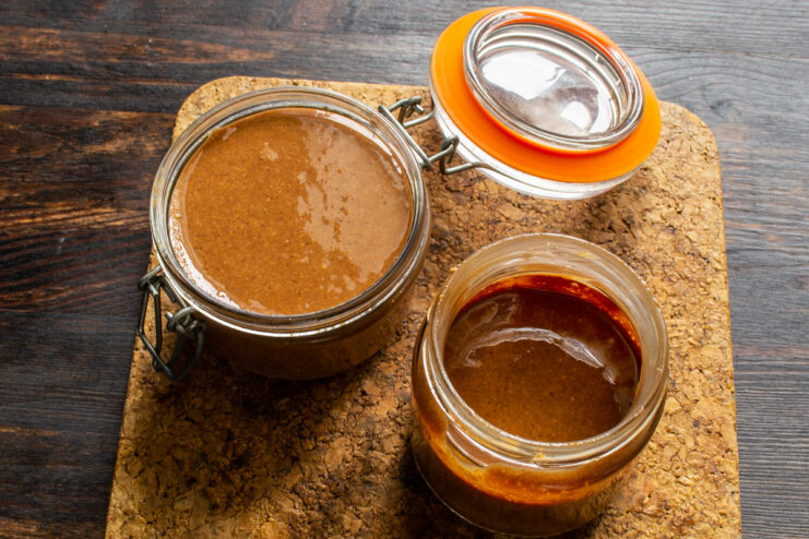Two glass jars filled with freshly made chocolate peanut butter.