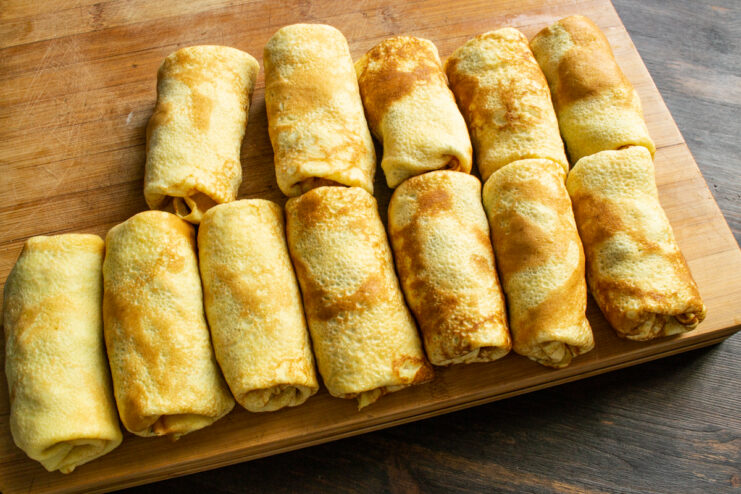 Folded Crepe Envelopes Stuffed crepes folded into neat envelopes on a wooden board