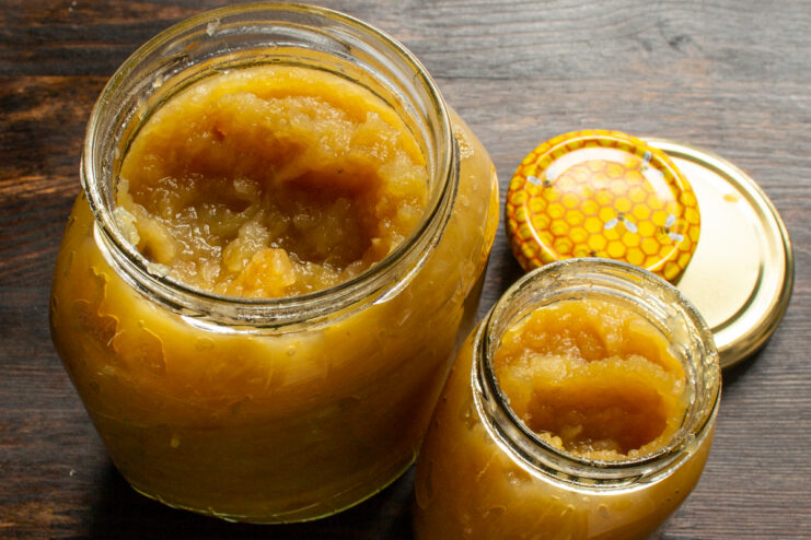 Portioning hot apple butter into jars Hot apple butter being ladled into clean glass jars for long-term storage.