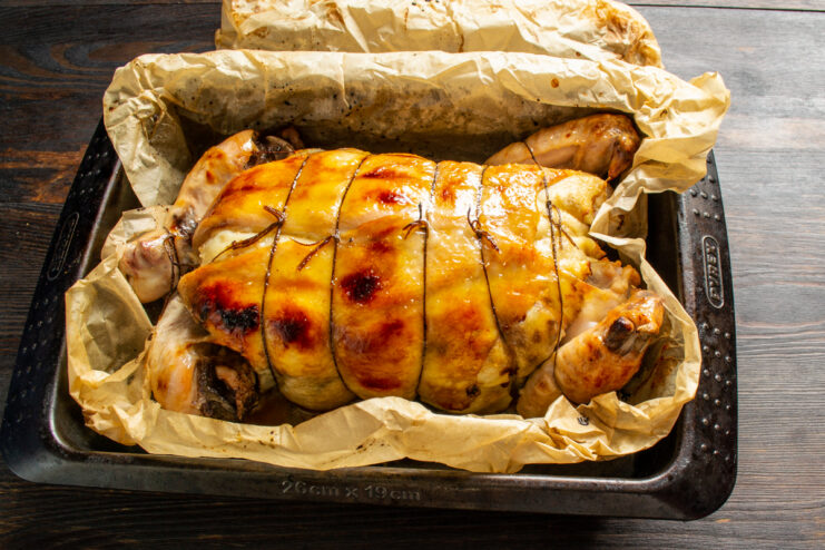 Fully roasted golden stuffed chicken in a baking dish.