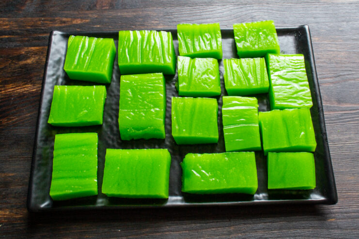 Ready to serve Finished green apple marmalade cubes arranged on a dark plate.