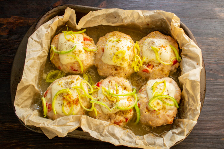 The final touch Finished meatballs with melted cheese and fresh herbs in a dish