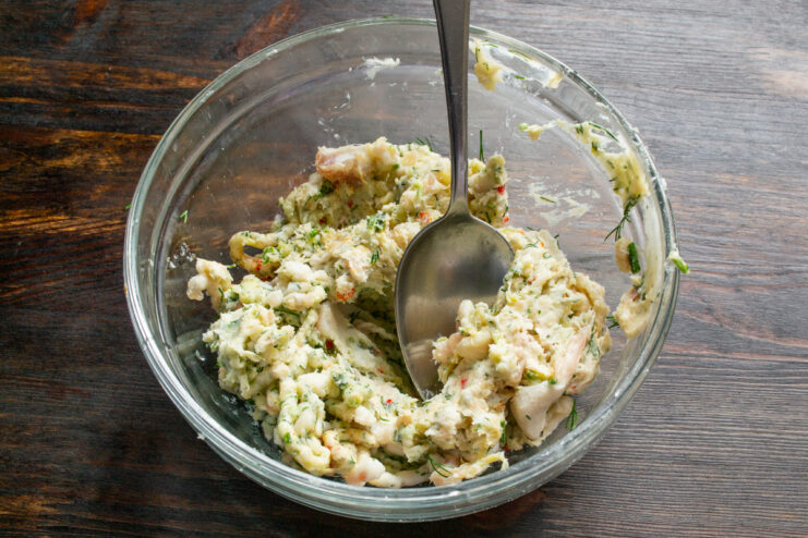 Grinding seasoned pork fat with herbs through a meat grinder