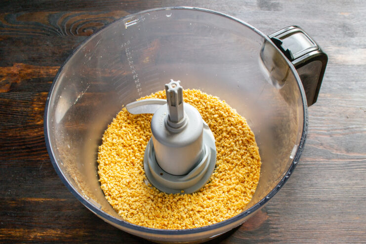 Grinding the roasted peanuts Finely ground roasted peanuts in a food processor bowl