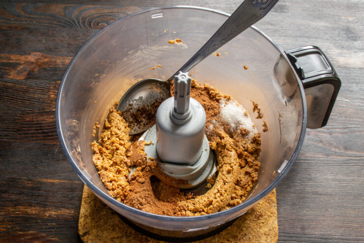 Cocoa powder added on top of the peanut mixture in a blender bowl.