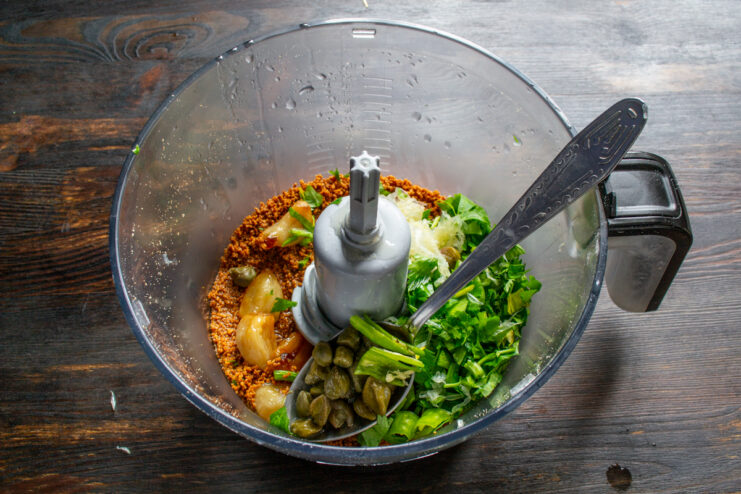 Adding savory flavor boosters Capers and chopped fresh chili pepper in a blender bowl