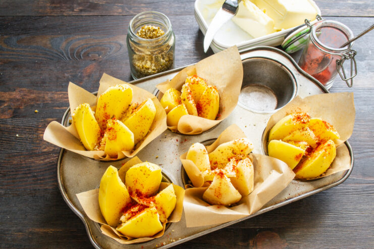 Sprinkling sweet red paprika over sliced potatoes