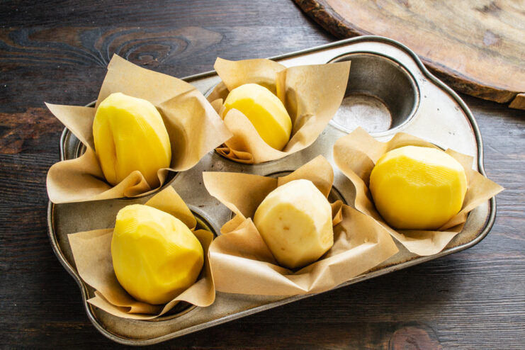 Pressing whole potatoes into parchment-lined muffin tin cups