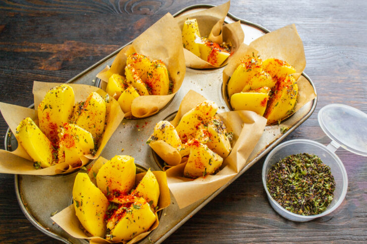 Seasoning potatoes with dried thyme in a muffin tin