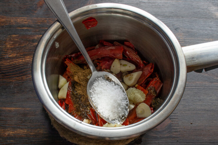 Seasoning with sea salt Adding coarse sea salt from a spoon into the chili sauce