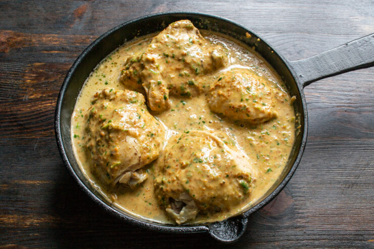 Simmering chicken in peanut sauce Chicken covered in a rich peanut sauce simmering in a skillet