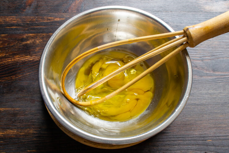 Whisking eggs in a bowl and reserving some for the egg wash