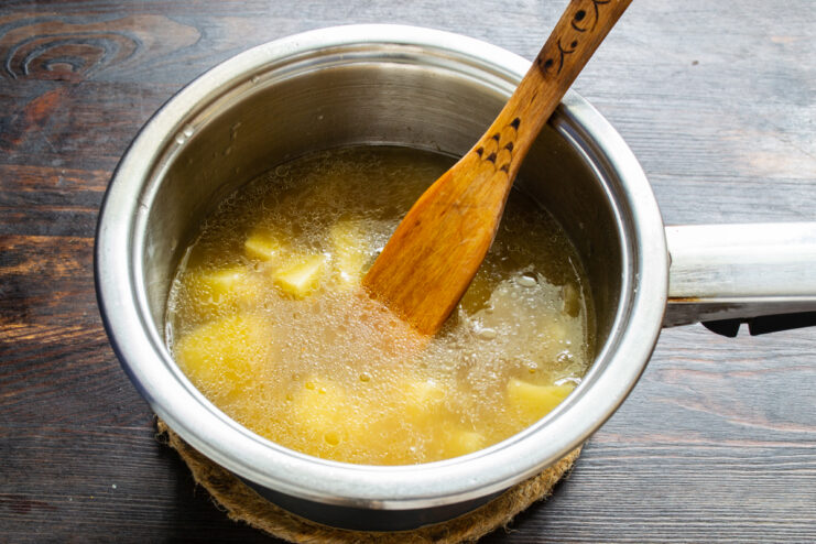 Pouring broth Pouring chicken broth over diced potatoes and onions in a pot