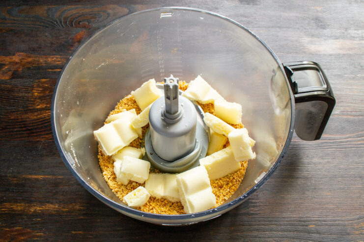 Adding white chocolate to warm peanuts Pieces of white chocolate added to crushed peanuts in a blender