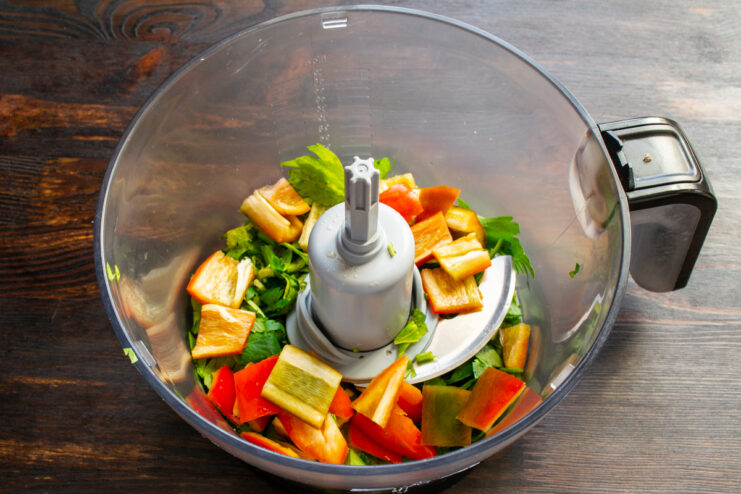 Adding chopped hot peppers to the blender Diced hot peppers added to the celery in the blender bowl.