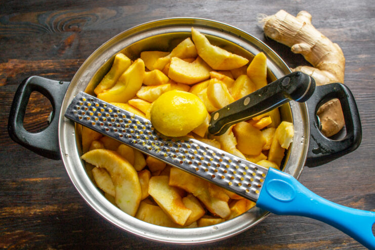 Squeezing lemon juice to balance sweetness A zested lemon and a grater placed over the pot of apples.