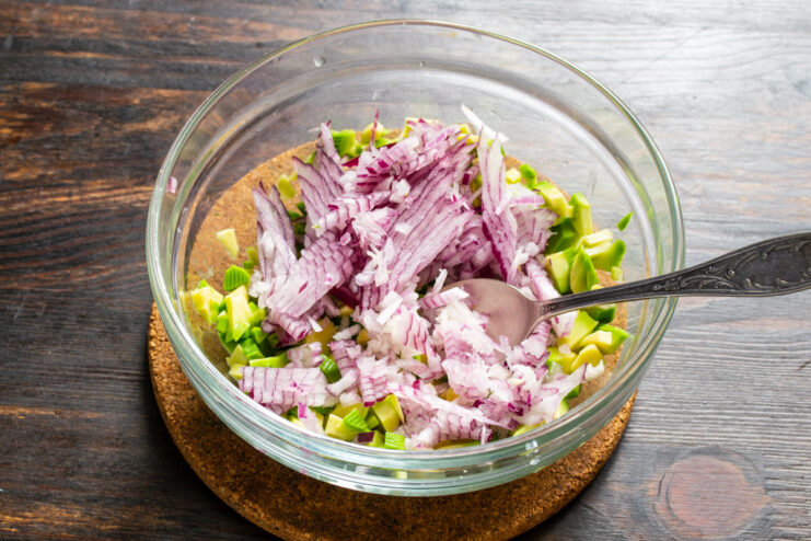 Adding Red Onion Finely diced red onion added to avocado in a bowl