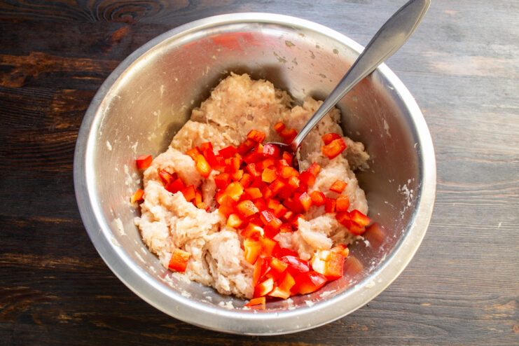 Adding bell pepper to the meat Ground meat mixed with finely diced red bell pepper