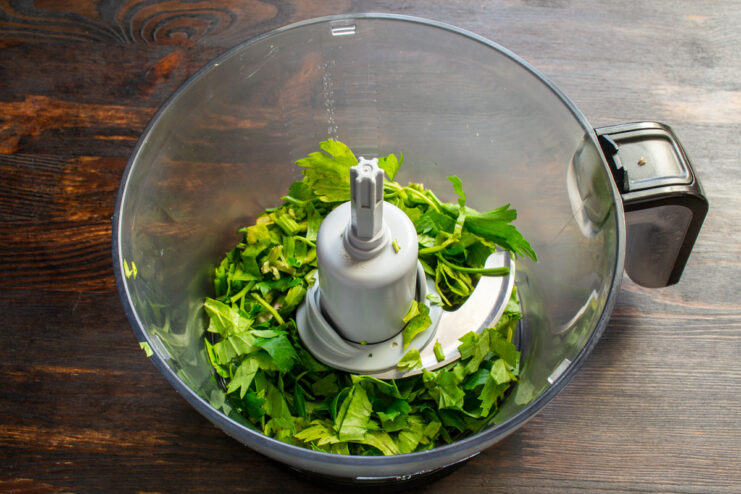 Blending fresh celery greens Chopped fresh celery greens placed inside a food processor bowl.