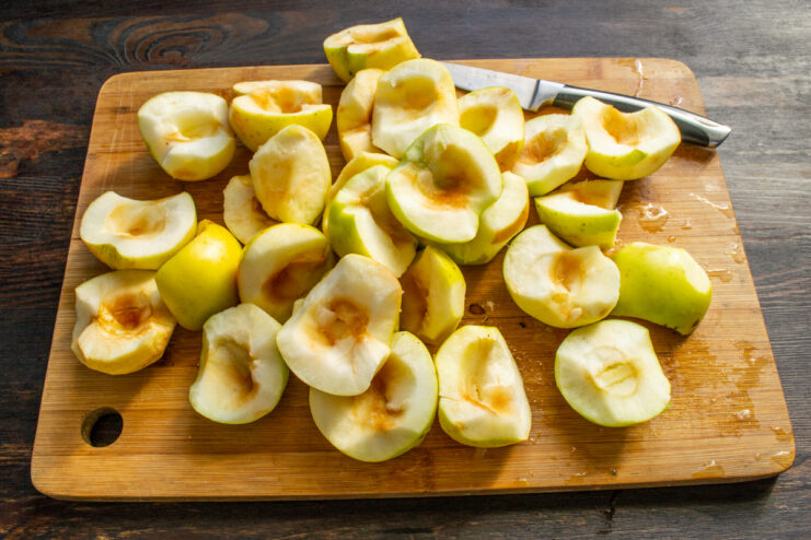 Preparing the apples by removing the core Apple wedges with cores removed resting on a wooden cutting board.