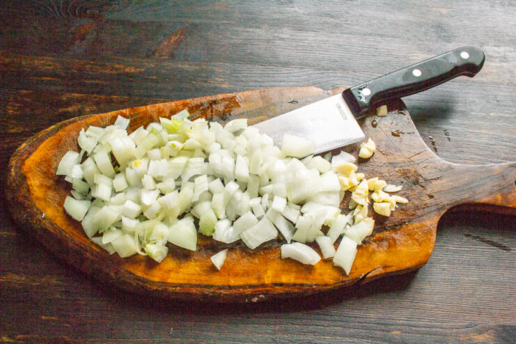 Chopping the Vegetables Diced yellow onions and minced garlic cloves on a wooden board