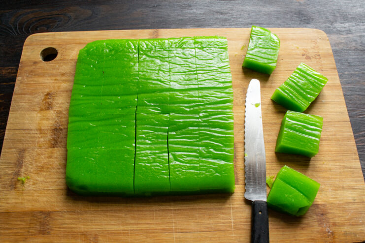 Cutting into portions Slicing a block of green marmalade into neat squares with a knife.