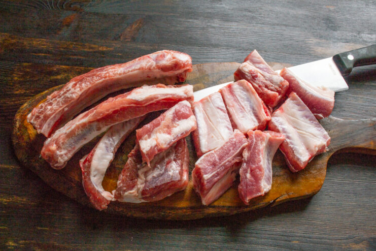 Preparing the Meat Slicing a rack of pork ribs into individual portions on a cutting board