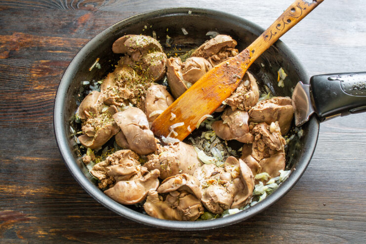 Sautéing liver with aromatic herbs Chicken livers cooking in a skillet with onions and herbs