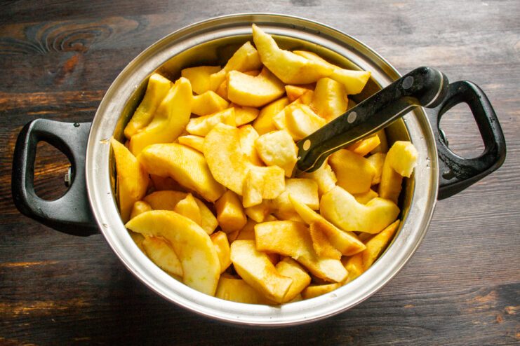 Adding water to the apple slices Peeled and chopped apple slices placed in a metal cooking pot.