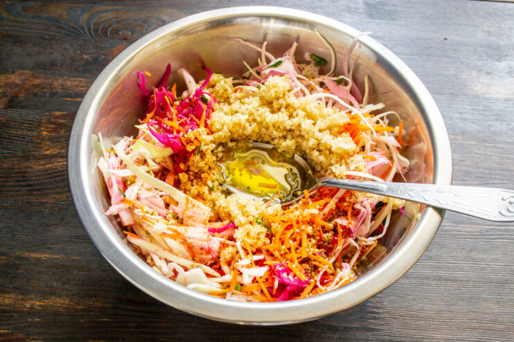 Extra virgin olive oil being poured over the quinoa and vegetable salad.