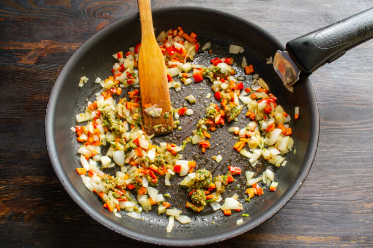 Adding Zesty Flavors Sautéed vegetables in a pan mixed with a spoonful of adjika paste