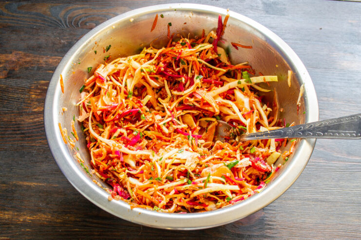 Tossed vegetable salad with quinoa in a large metal bowl.