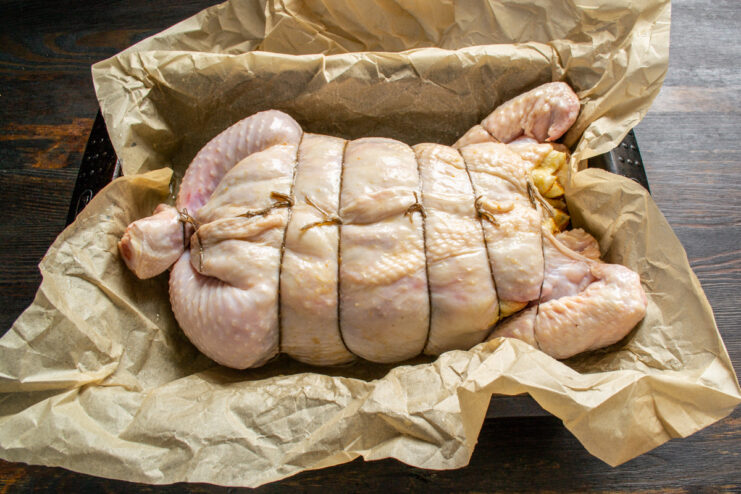 Prepared stuffed chicken in a baking dish lined with parchment paper.