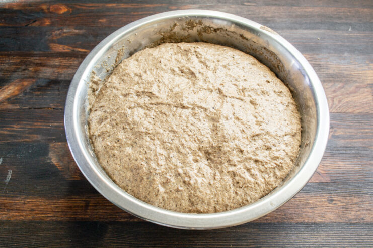 Well-risen rye dough in a metal mixing bowl