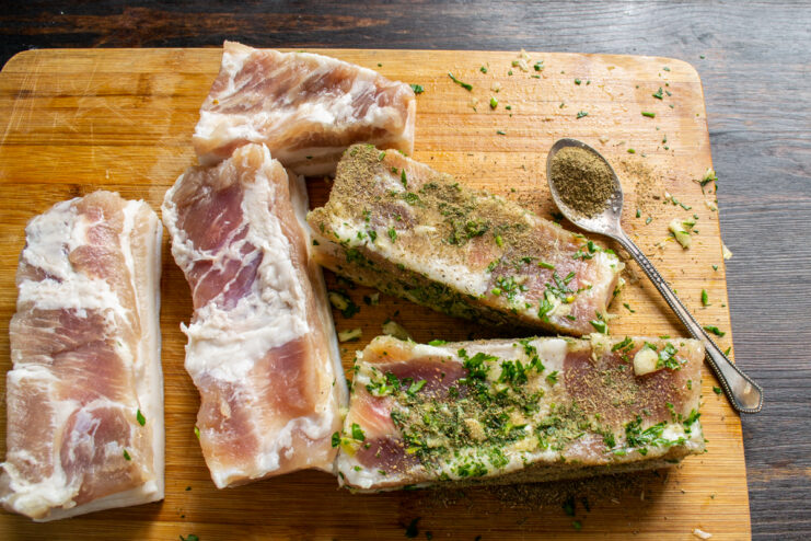 Dusting the seasoned pork belly with a fine powder of ground bay and caraway